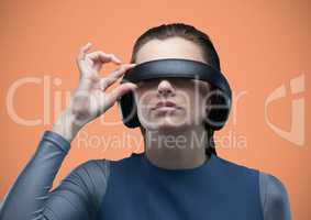 Woman in virtual reality headset against orange background