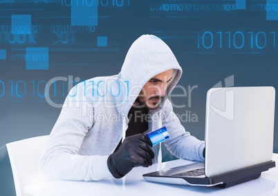 hacker holding a 3d credit card and using a laptop in front of blue digital background