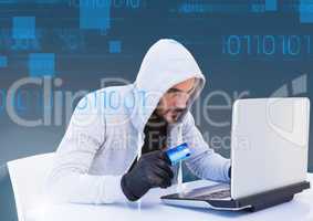 hacker holding a 3d credit card and using a laptop in front of blue digital background