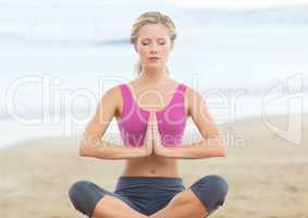 Woman meditating against blurry beach