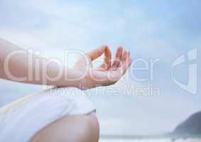 Hand and knee of meditating woman against blurry beach