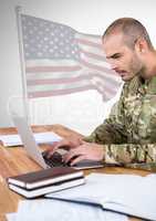 Military working on his laptop against american flag