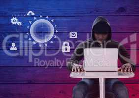 Hacker using a laptop in front of wood background with digital icons