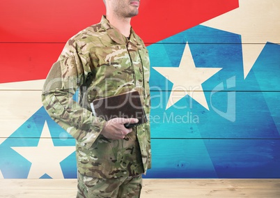 Side view of soldier holding a book in front of american flag
