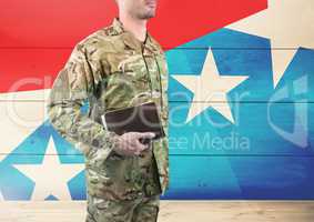 Side view of soldier holding a book in front of american flag