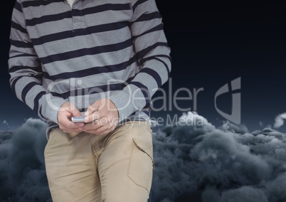 Part of a man texting in front of dark cloud