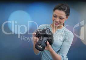 photographer smiling looking the photos on the camera. Blue blurred lights on back