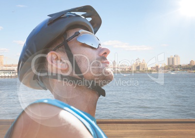Close up of cyclist against water and skyline with flare