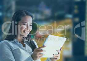 Smiling woman using a digital tablet with buildings in background