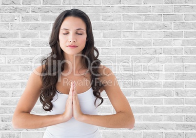 Woman meditating against white brick wall