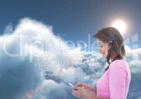 Smiling woman texting with 3D clouds and sun in background