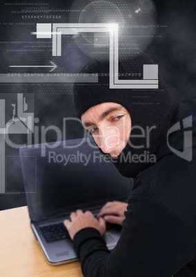 Hacker looking the lens and using a laptop in front of 3D black background