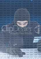 Hacker using a laptop and holding a credit card behind a digital screen