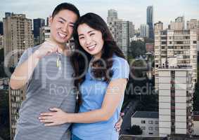 Couple Holding Apartment Keys with city