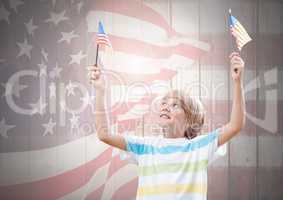 Happy boy holding two 3d american flags against a wooden background