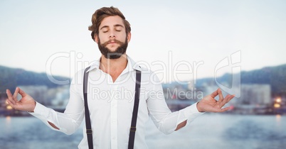 Millennial man meditating against blurry skyline