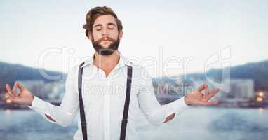 Millennial man meditating against blurry skyline