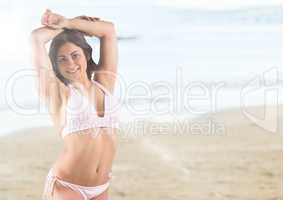 Woman in light pink bikini against blurry beach with flare
