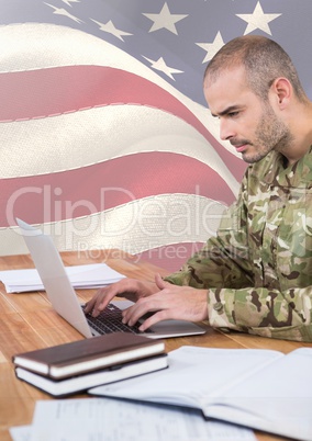 Soldier using a laptop in front of american flag