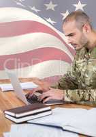 Soldier using a laptop in front of american flag