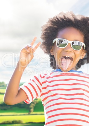 Boy in sunglasses making peace sign against fields with flare
