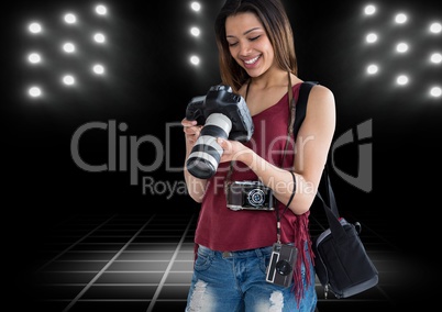 happy young photographer looking the photos on the camera with stadium lights behind