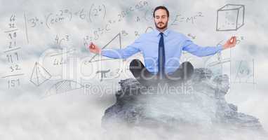 Business man meditating on mountain peak among clouds against math doodles