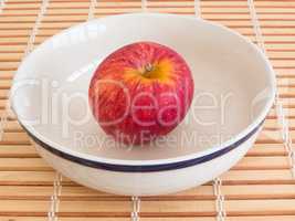 Red apple inside bowl on wooden table