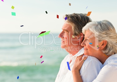 Confetti against elderly couple looking out to sea