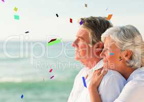 Confetti against elderly couple looking out to sea