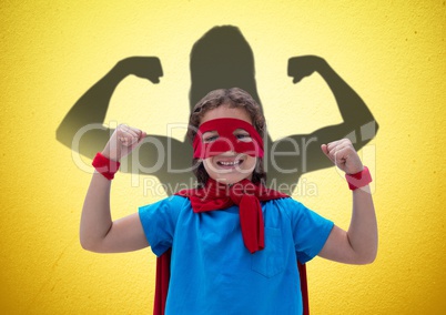 happy girl dressing up like a superwoman in front of fists draw on yellow wall