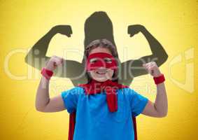 happy girl dressing up like a superwoman in front of fists draw on yellow wall