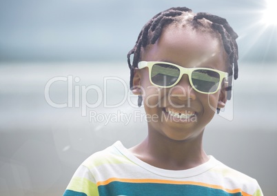Close up of boy in sunglasses against blurry beach with flare