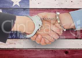 Handshake with handcuffs against wooden american flag background