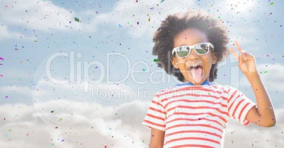 Boy in sunglasses making peace sign against sky with flare and confetti