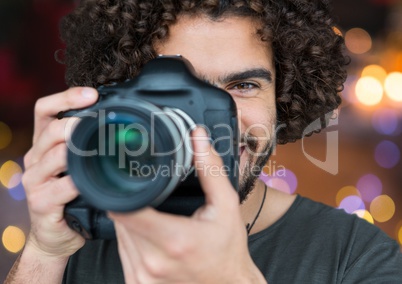 photographer smiling and taking a photo foreground. City blurred lights behind