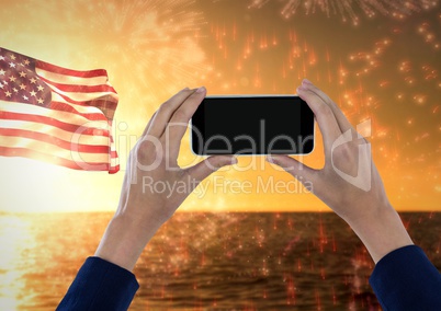 Hands holding a mobile phone against the sea and the american flag