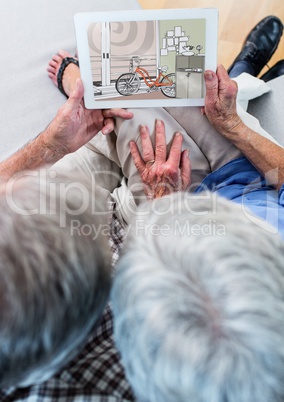 senior couple on the sofa with tablet (top view). On tablet the design of the new room (color:green,