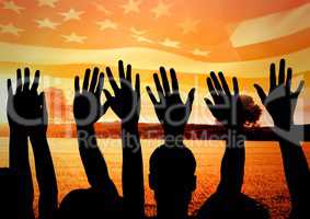 Silhouettes of hands  against american flag and sunset