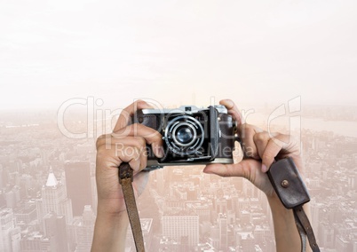 Hands of photographer taking picture against buildings in background