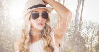 Close up of woman in summer clothes against blurry trees with flare