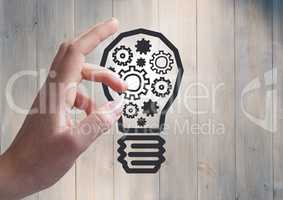 3d Hand pointing at cogs in lightbulb graphic and flare against grey wood panel
