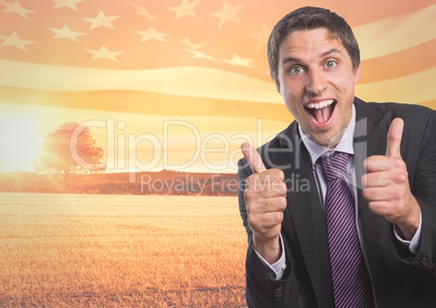 Happy business man with thumbs up against sunset landscape