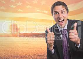 Happy business man with thumbs up against sunset landscape