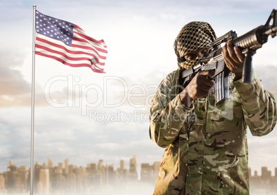 Military with covered face holding and pointing a weapon against american flag