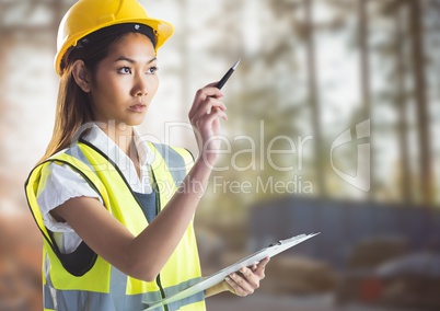 Female builder with clipboard against blurry building site