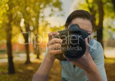 photographer taking a photo foreground. She is inm the park. With bokeh overlap