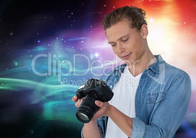 Smiling photographer looking at his camera with lights in colors in background