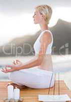 Woman meditating with candles on beach