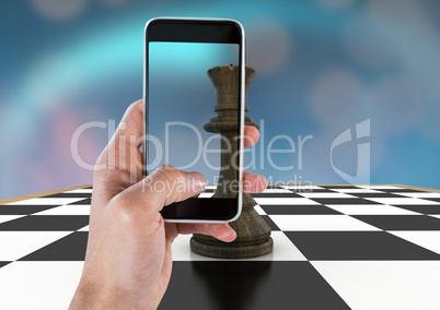 Hand with phone against chess piece and blue bokeh